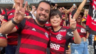 O governador do Rio, Cláudio Castro, gesticula em foto com seu filho na arquibancada; ambos vestem camisa do Flamengo