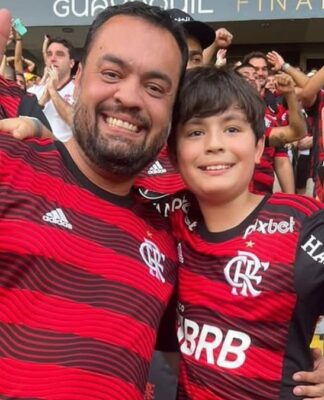 O governador do Rio, Cláudio Castro, gesticula em foto com seu filho na arquibancada; ambos vestem camisa do Flamengo