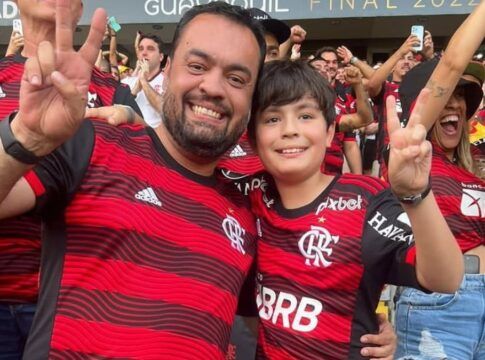 O governador do Rio, Cláudio Castro, gesticula em foto com seu filho na arquibancada; ambos vestem camisa do Flamengo