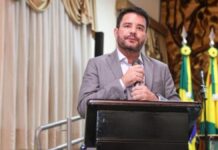 Governador do Acre segura o microfone com as duas mãos durante evento