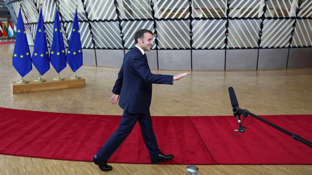 Macron caminha sobre tapete vermelho com bandeiras da União Europeia ao fundo