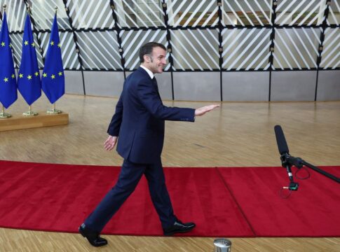 Macron caminha sobre tapete vermelho com bandeiras da União Europeia ao fundo