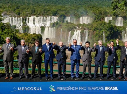 Fotografia oficial dos presidentes e chefes de delegação dos Estados Partes do Mercosul, todos em pé, de mãos dadas, à frente das Cataratas do Iguaçu