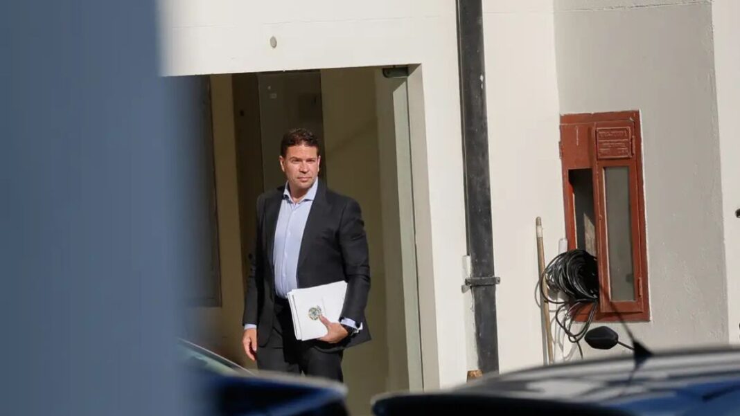 Alexandre Ramagem segura papéis na porta de um edifício