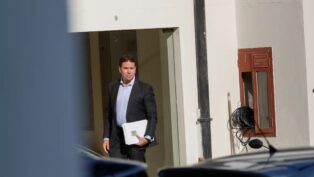 Alexandre Ramagem segura papéis na porta de um edifício