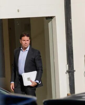 Alexandre Ramagem segura papéis na porta de um edifício