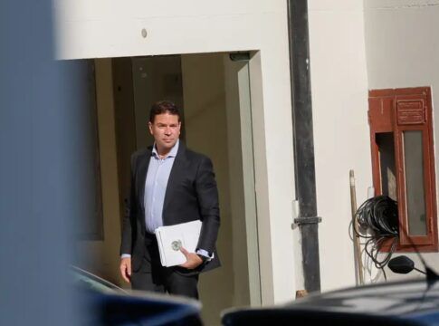 Alexandre Ramagem segura papéis na porta de um edifício