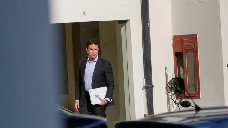 Alexandre Ramagem segura papéis na porta de um edifício