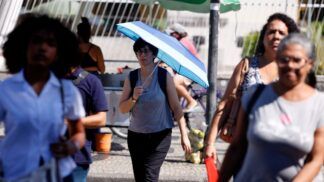 Pessoas com calor nas ruas do Rio, uma delas com uma sombrinha
