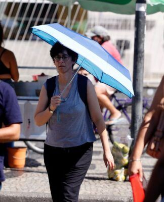 Pessoas com calor nas ruas do Rio, uma delas com uma sombrinha