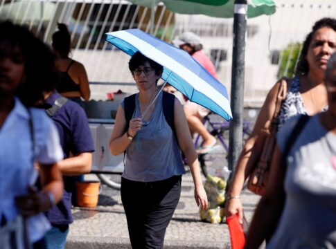 Pessoas com calor nas ruas do Rio, uma delas com uma sombrinha