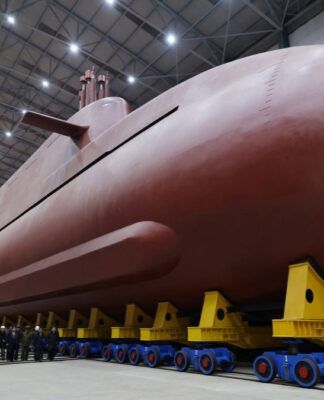 Submarino nuclear, de cor vermelha, colocado sob apoios e observado pelo líder da Coreia do Norte