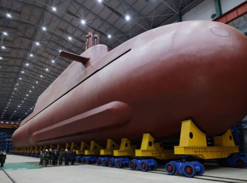 Submarino nuclear, de cor vermelha, colocado sob apoios e observado pelo líder da Coreia do Norte