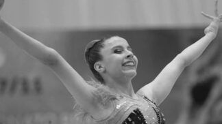 Ginasta finaliza apresentação com as duas mãos para o ar