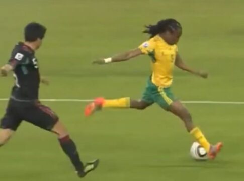 Jogadores do México e da África do Sul correndo atrás da bola