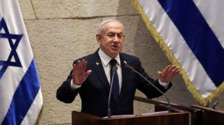 Benjamin Netanyahu falando em palanque com uma bandeira de Israel em cada lado