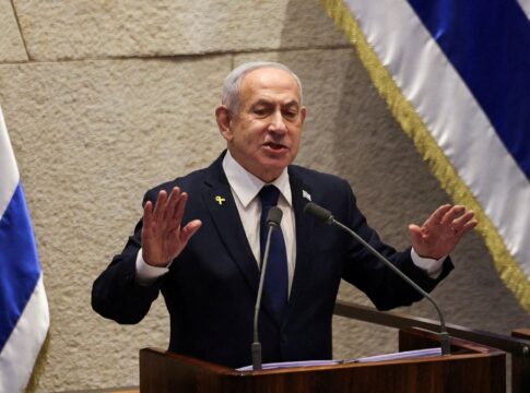 Benjamin Netanyahu falando em palanque com uma bandeira de Israel em cada lado