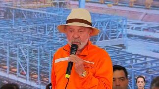 Presidente Lula, trajado de uniforme laranja e chapéu de palha, discursando com lágrimas nos olhos