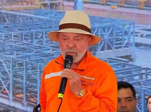Presidente Lula, trajado de uniforme laranja e chapéu de palha, discursando com lágrimas nos olhos
