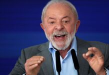 Lula gesticula com as duas mãos diante de microfone