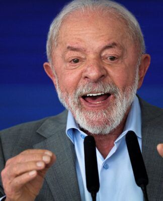 Lula gesticula com as duas mãos diante de microfone