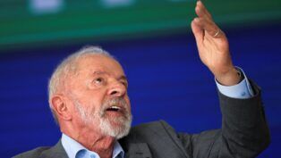 Lula aponta para o alto com a mão esquerda durante discurso