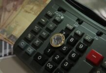 Imagem de uma moeda de um real colocada sobre uma calculadora