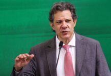Ministro Fernando Haddad gesticula enquanto fala ao microfone em evento oficial