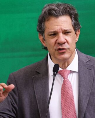 Ministro Fernando Haddad gesticula enquanto fala ao microfone em evento oficial