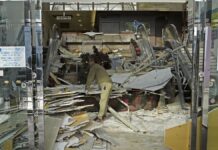 Trabalhador limpa entrada de sua loja após estrago causado por terremoto