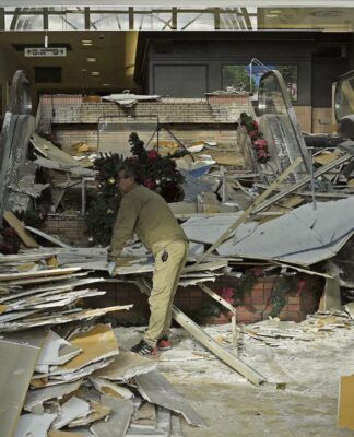 Trabalhador limpa entrada de sua loja após estrago causado por terremoto
