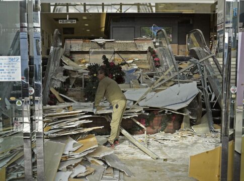 Trabalhador limpa entrada de sua loja após estrago causado por terremoto
