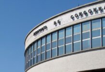 A imagem é um plano médio que foca na parte superior da fachada curva do terminal de passageiros do Aeroporto de Congonhas (CGH), em São Paulo, em um dia claro e ensolarado.