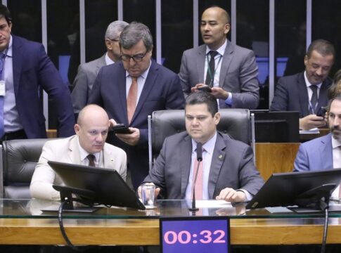 A foto mostra um grupo de parlamentares sentados e em pé, reunidos em um ambiente que se assemelha à mesa diretora ou a uma comissão dentro do Congresso Nacional .