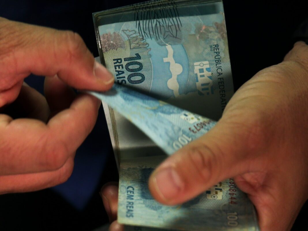 notas de 100 reais nas mãos de uma pessoa
