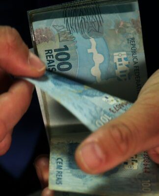 notas de 100 reais nas mãos de uma pessoa