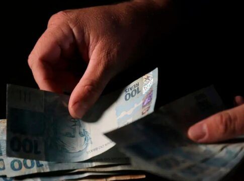 imagem de uma mão manipulando notas de dinheiro