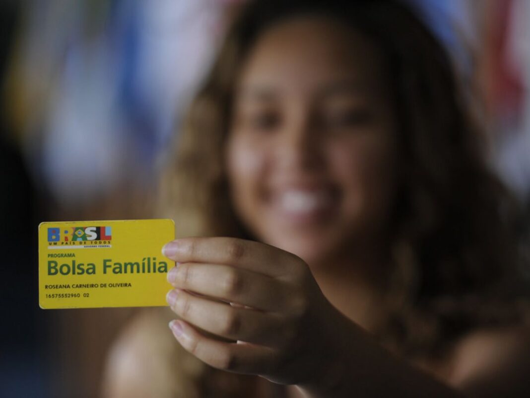 Em imagem mulher mostra seu cartão do Bolsa Família