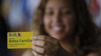 Em imagem mulher mostra seu cartão do Bolsa Família