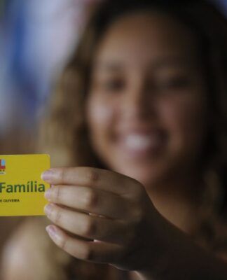 Em imagem mulher mostra seu cartão do Bolsa Família