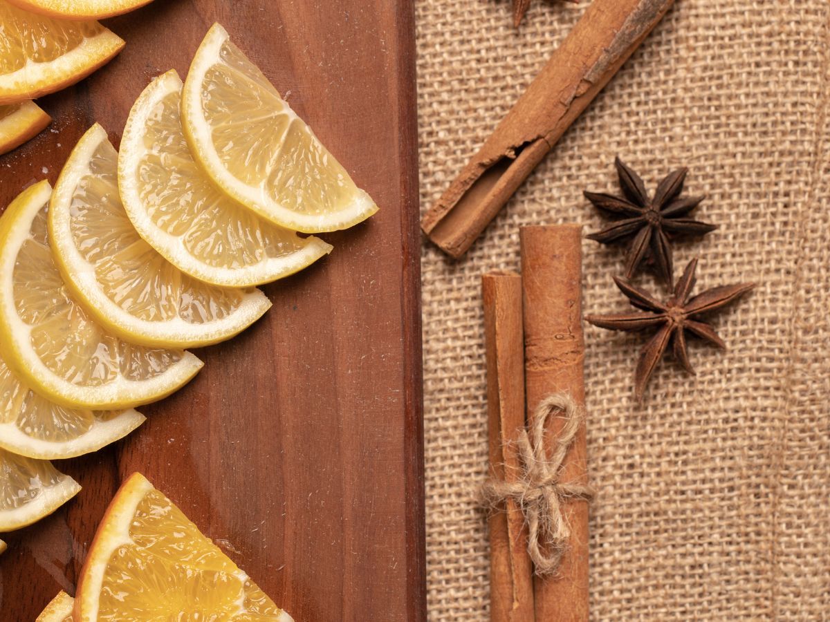 Na foto há laranjas e limão cortados em rodelas. Tem também anis e canela.