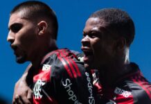 A foto em plano médio captura dois jogadores de futebol do time do Flamengo celebrando um momento de gol ou vitória com grande intensidade emocional.