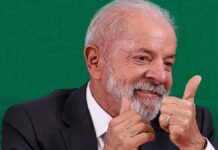 A foto mostra um plano médio do presidente Luiz Inácio Lula da Silva, que está sorrindo e gesticulando com as duas mãos em um sinal de aprovação (