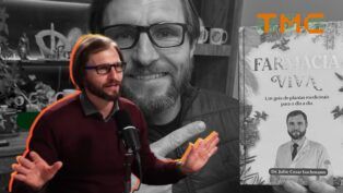 O Dr. Júlio Luchmann aparece do peito para cima, posicionado à esquerda. Ele está em meio a uma fala entusiasmada, com as duas mãos levantadas e as palmas voltadas para a frente, em um gesto de explicação ou ênfase.