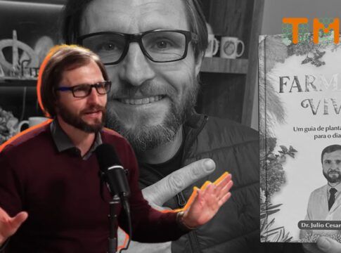 O Dr. Júlio Luchmann aparece do peito para cima, posicionado à esquerda. Ele está em meio a uma fala entusiasmada, com as duas mãos levantadas e as palmas voltadas para a frente, em um gesto de explicação ou ênfase.