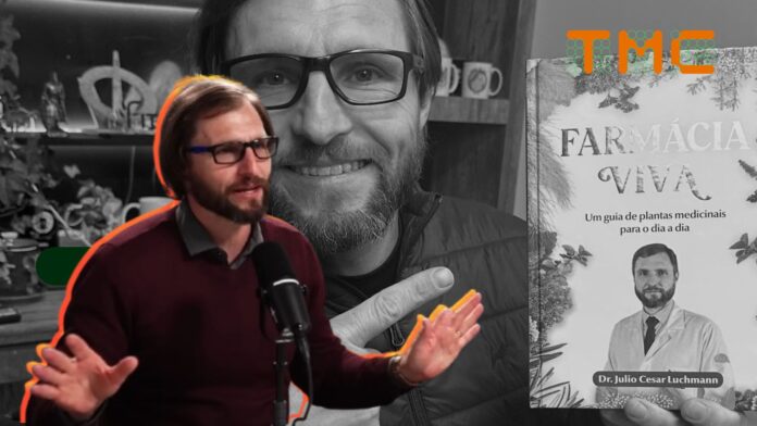 O Dr. Júlio Luchmann aparece do peito para cima, posicionado à esquerda. Ele está em meio a uma fala entusiasmada, com as duas mãos levantadas e as palmas voltadas para a frente, em um gesto de explicação ou ênfase.