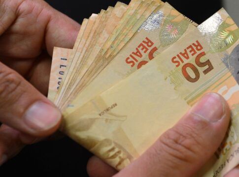 Duas mãos contam notas de 50 reais