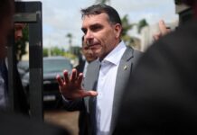 Flávio Bolsonaro faz gesto com a mão ao falar com os jornalistas