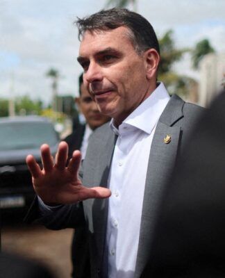 Flávio Bolsonaro faz gesto com a mão ao falar com os jornalistas
