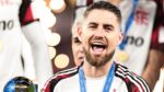 A imagem é um close-up frontal do jogador de futebol Jorge Luiz Frello Filho (Jorginho), meio-campista do Flamengo, em um momento de intensa celebração, após uma vitória na Copa Intercontinental.